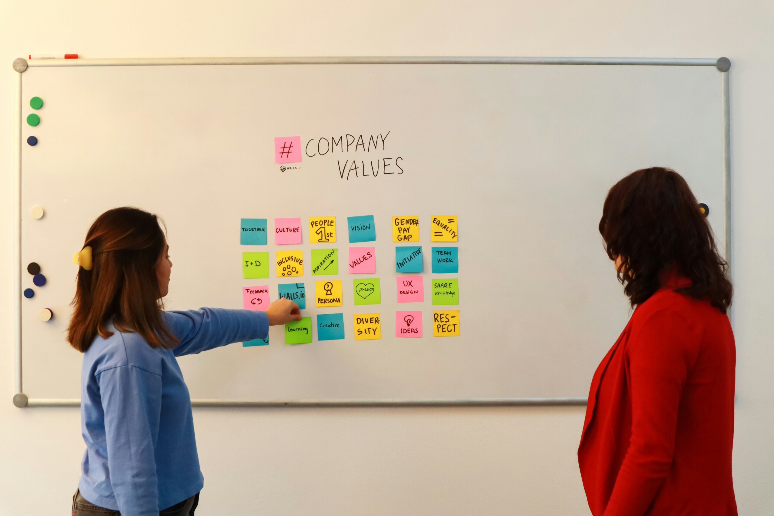 Deux entrepreneurs passionnés qui échangent devant un tableau blanc couvert de schémas et d