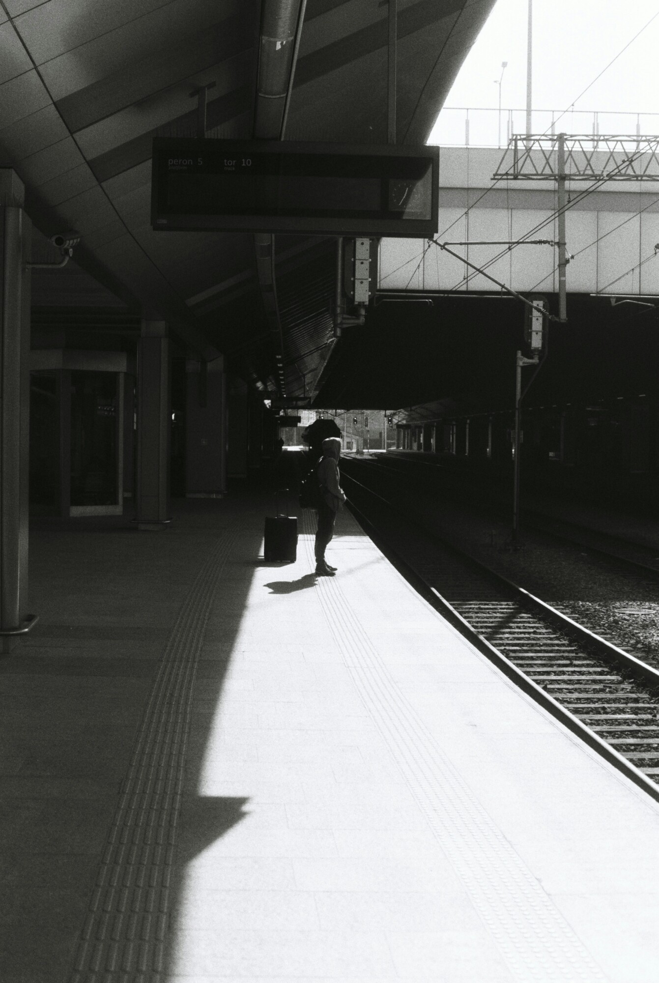 Man checking phone in a train station with blurred trains in background