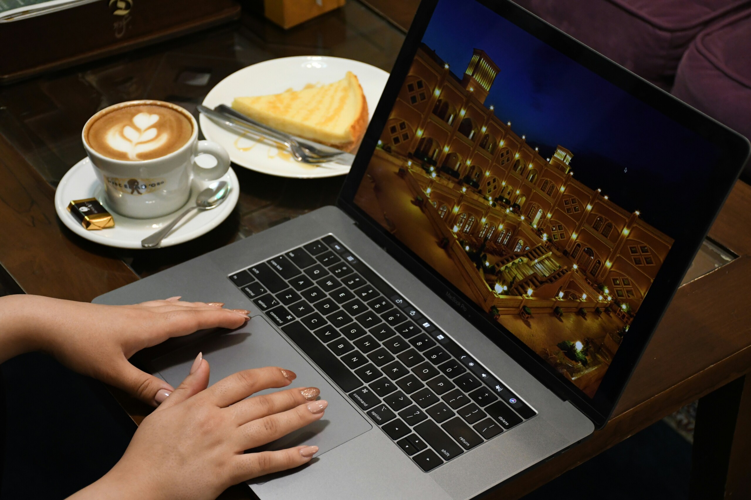 Close up of hands working on a laptop with a coffee cup on a wooden table