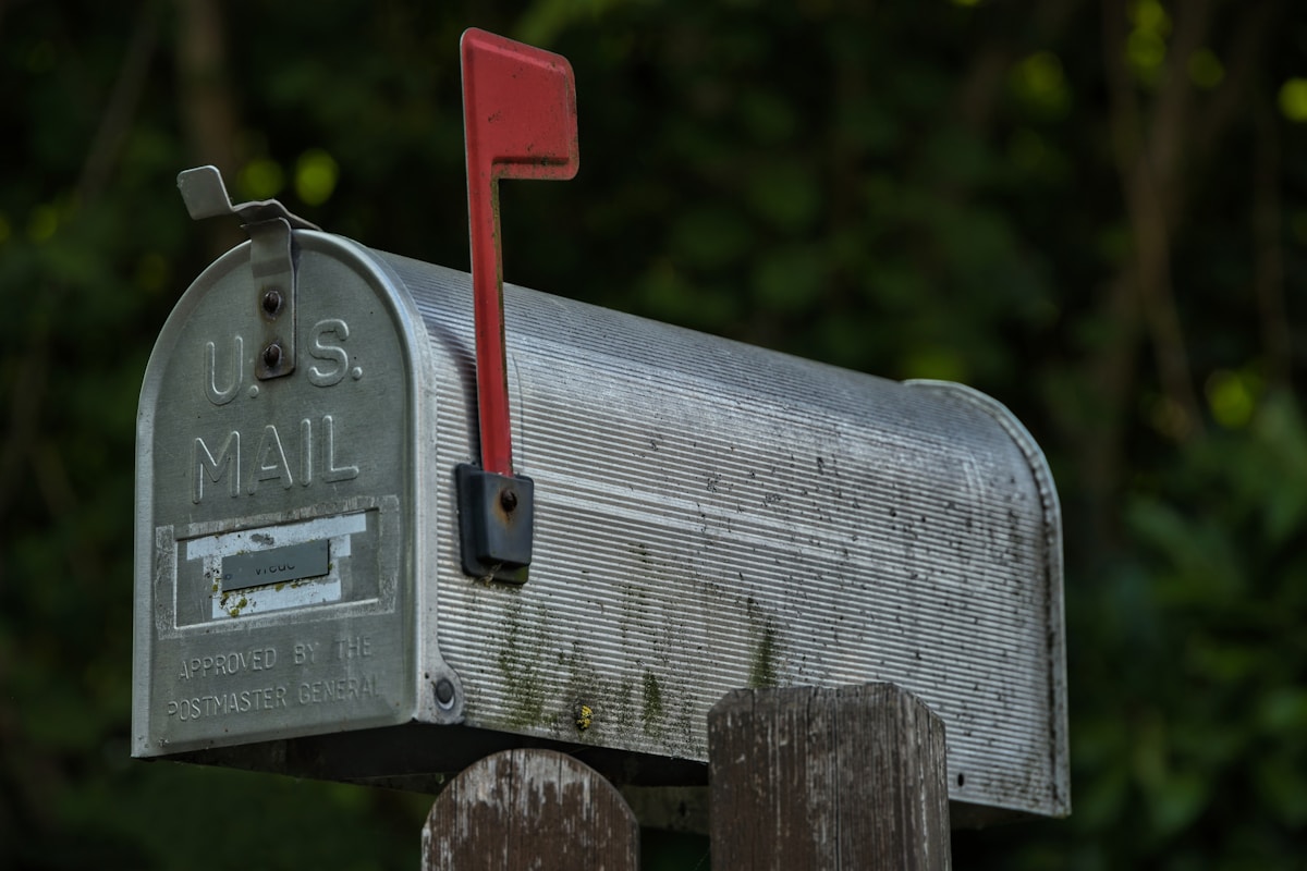 A weathered u.s. mailbox with a red flag.