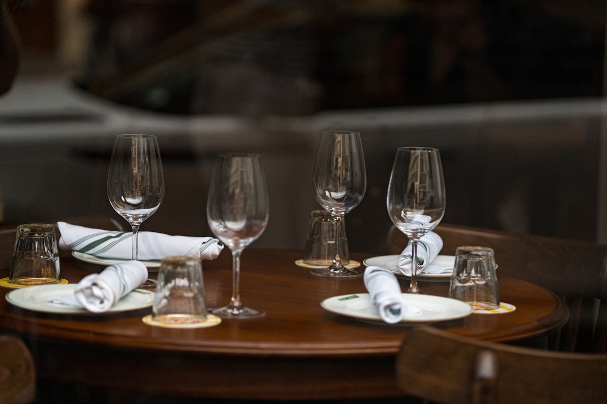 Table dressée avec verres à vin, assiettes et serviettes.