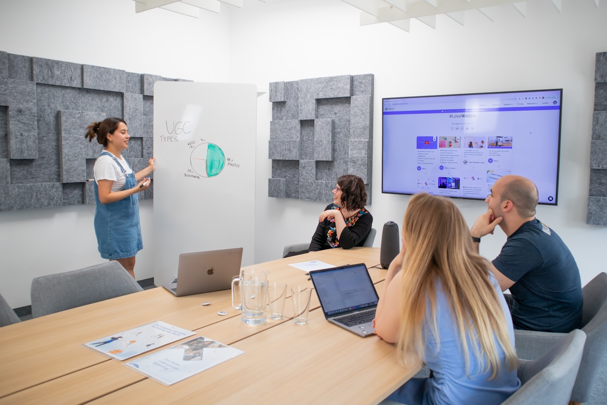 Réunion d'équipe dans un espace de travail moderne avec tableau blanc et écran.