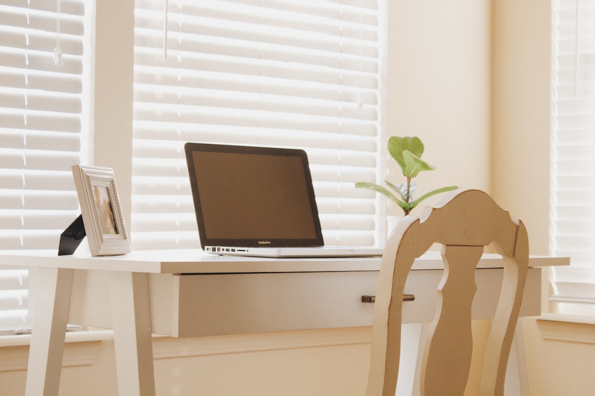 Bureau avec ordinateur portable, plante verte et cadre photo.