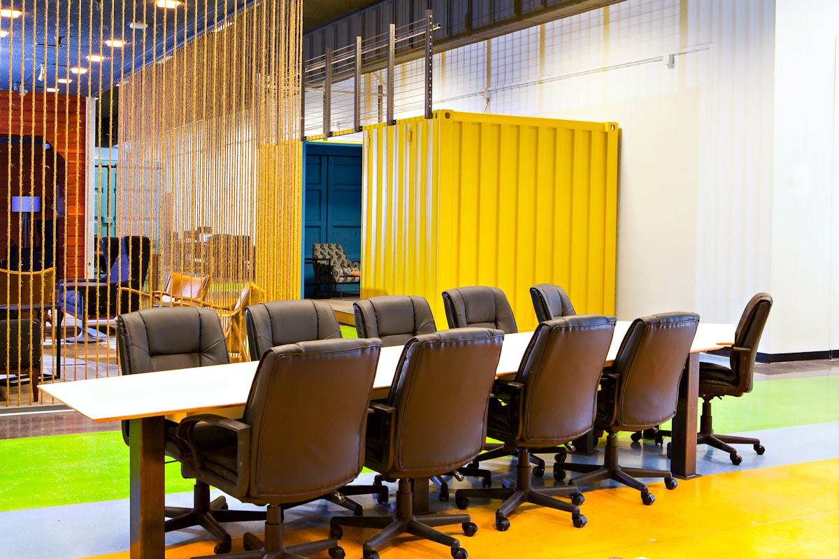 Salle de réunion moderne avec table de conférence et chaises en cuir.