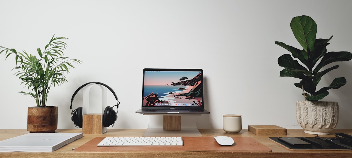 Bureau de travail avec ordinateur portable, plantes, casque audio et accessoires.