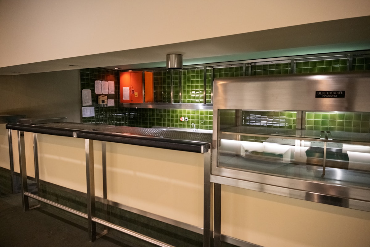 Cuisine industrielle avec comptoirs en métal et carreaux verts.
