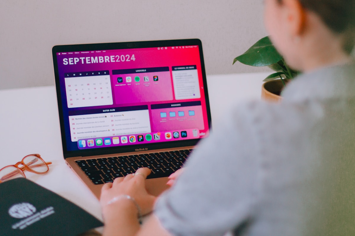Ordinateur portable affichant un calendrier de septembre 2024 sur un bureau avec une plante verte.