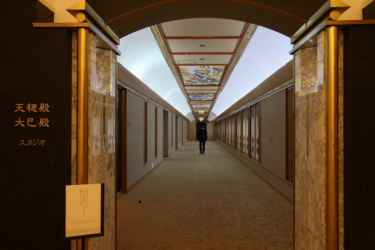 Couloir intérieur orné de motifs japonais avec un visiteur solitaire.