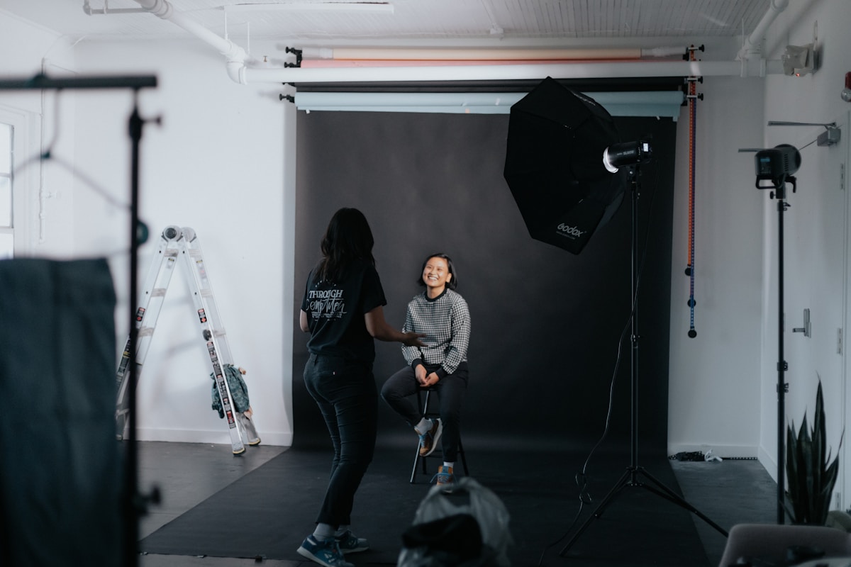 Deux femmes dans un studio de photographie, avec équipement et fond noir.