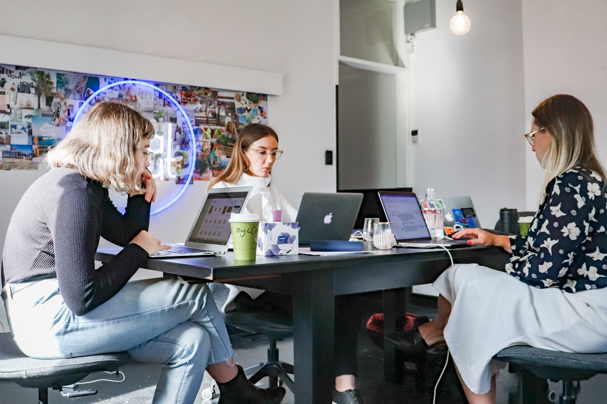 Trois jeunes femmes travaillant ensemble dans un espace de bureau moderne.