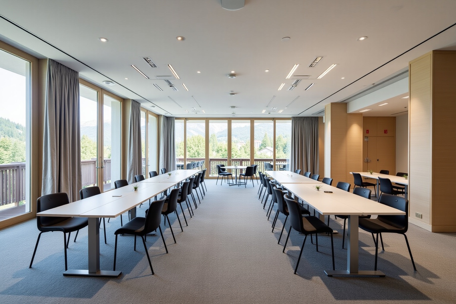Salle de réunion spacieuse avec grandes fenêtres, tables longues et chaises noires.