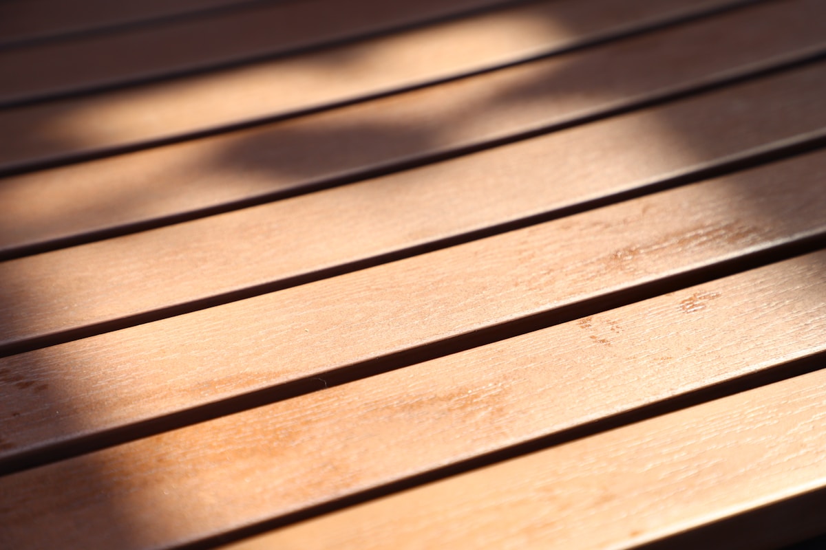 Planches de bois avec lignes sombres, surface texturée et éclairage chaud.