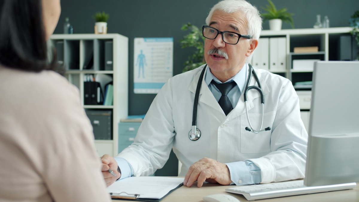 Médecin âgé en consultation avec un patient dans son cabinet médical.