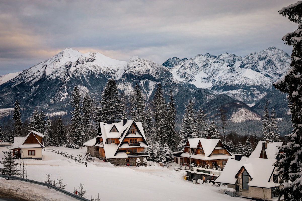 Village montagneux enneigé avec chalets traditionnels.