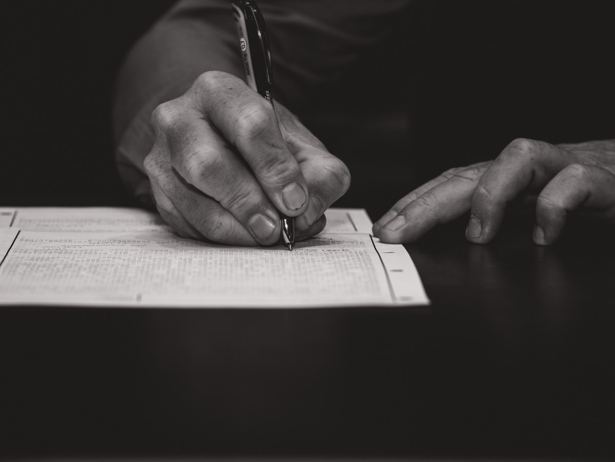 Une main écrivant avec un stylo plume sur du papier.