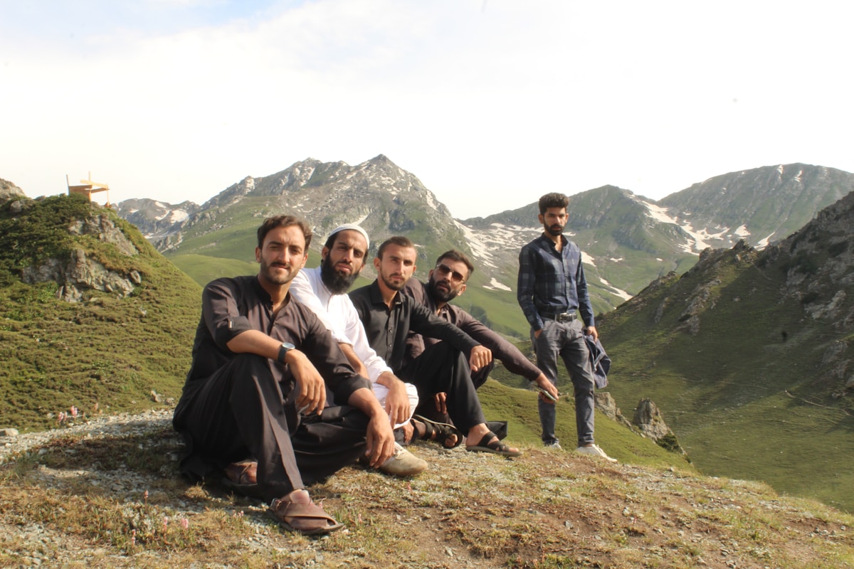 Groupe d'hommes assis sur une montagne avec un paysage montagneux en arrière-plan.