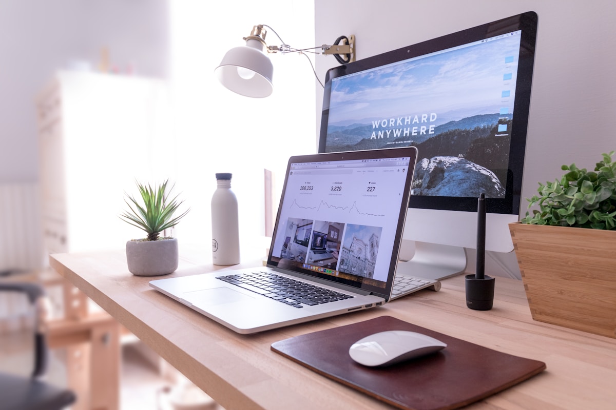 Bureau de travail avec ordinateur portable, lampe, plante et accessoires.