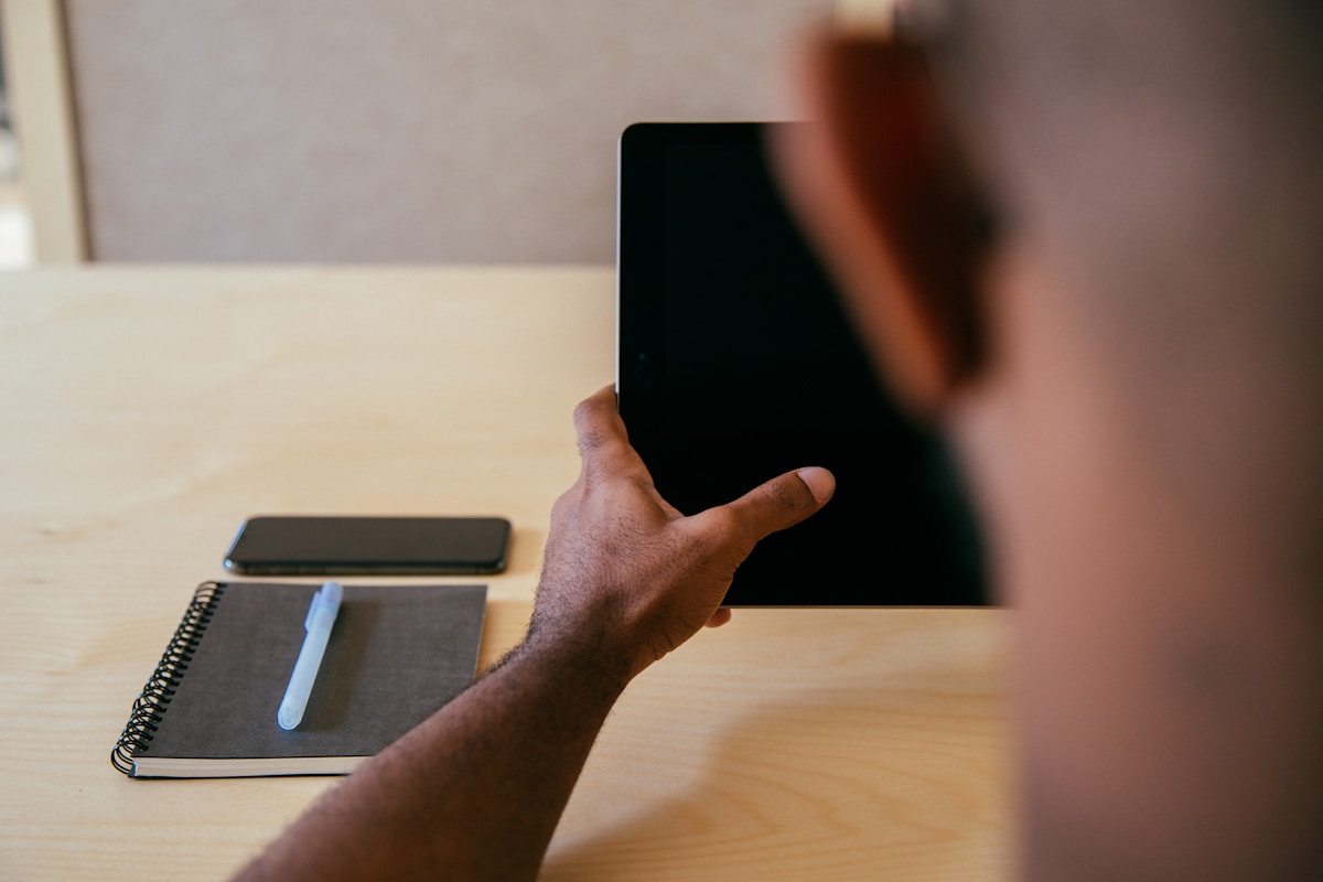 Personne tenant un téléphone portable sur un bureau avec un cahier.