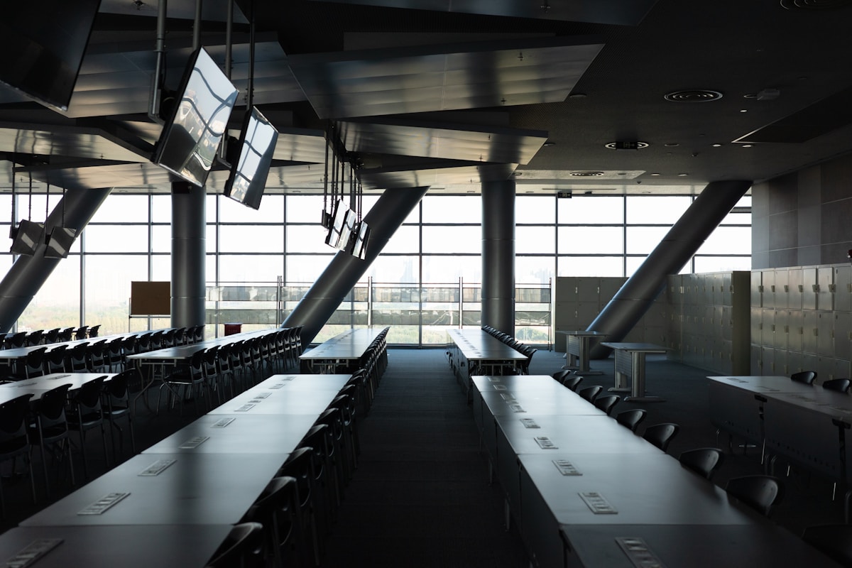 Salle de conférence moderne avec rangées de tables et de chaises.