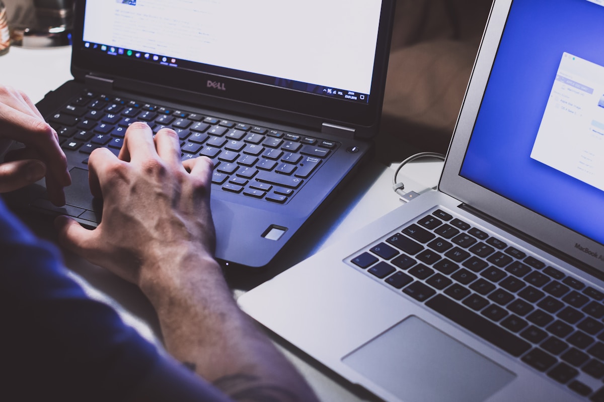 Mains sur un clavier d'ordinateur portable Dell, écran bleu en arrière-plan.