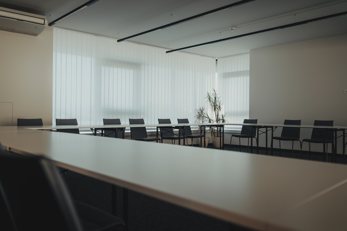 Salle de réunion moderne avec table de conférence et chaises noires.