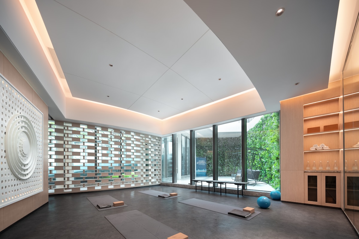Salle de yoga moderne avec mur décoratif et grandes fenêtres.