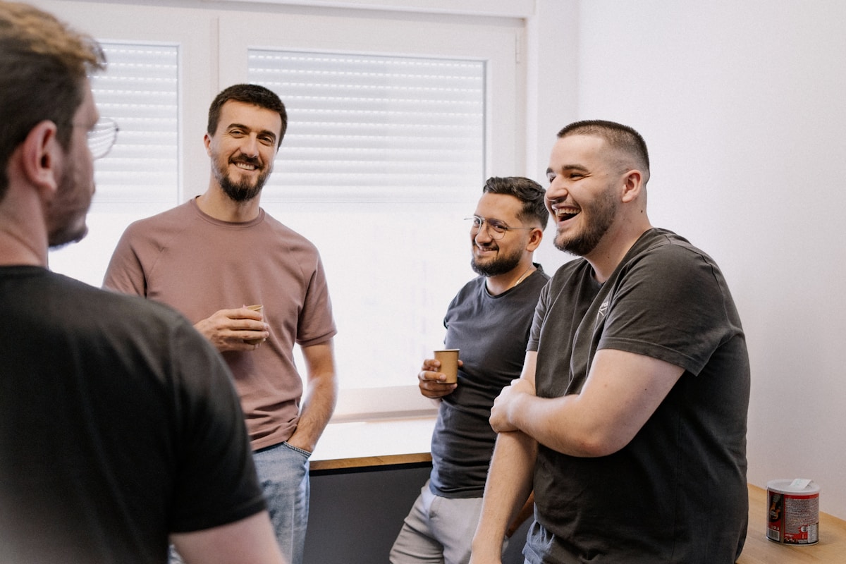 Groupe d'hommes souriants et discutant dans un bureau.