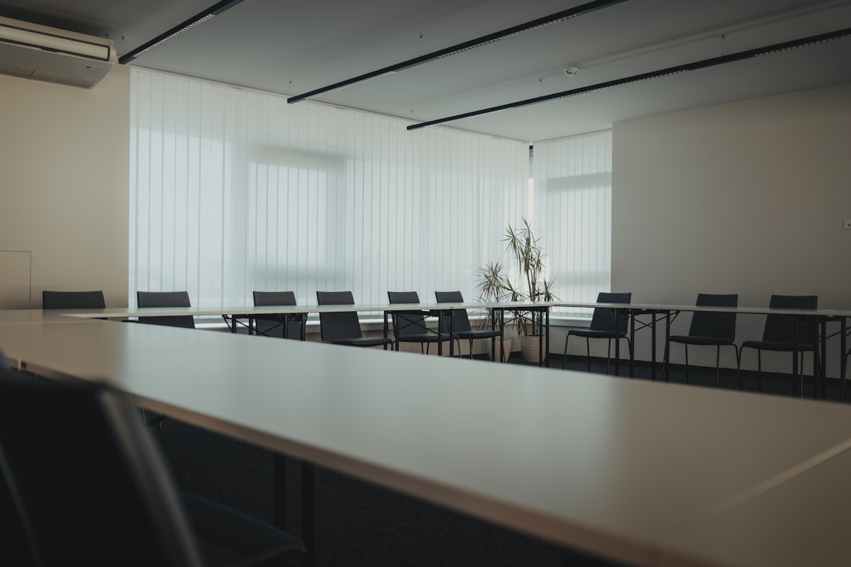 Salle de réunion moderne avec table de conférence et chaises noires.