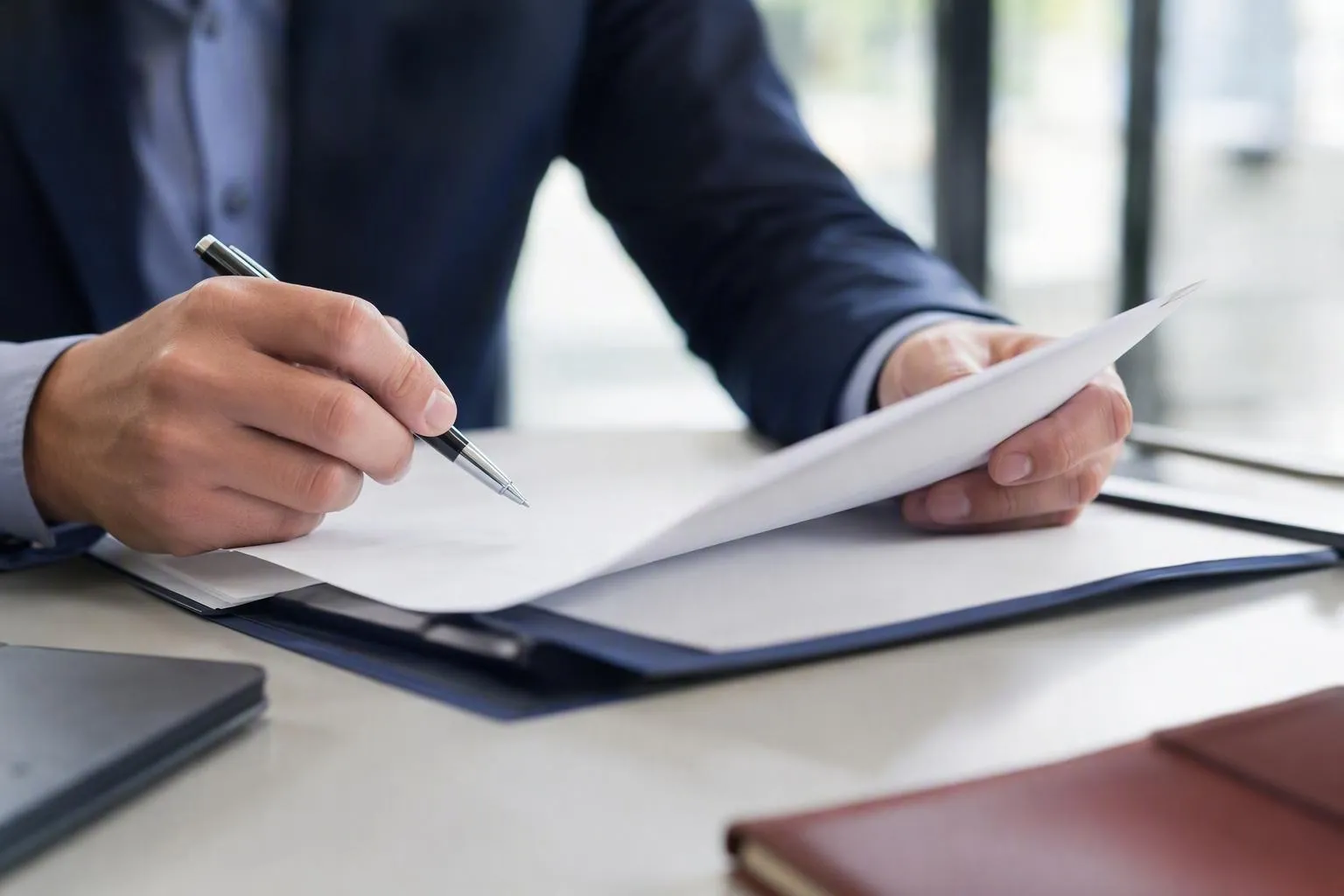 Mains d'un homme d'affaires signant un document important sur un bureau.