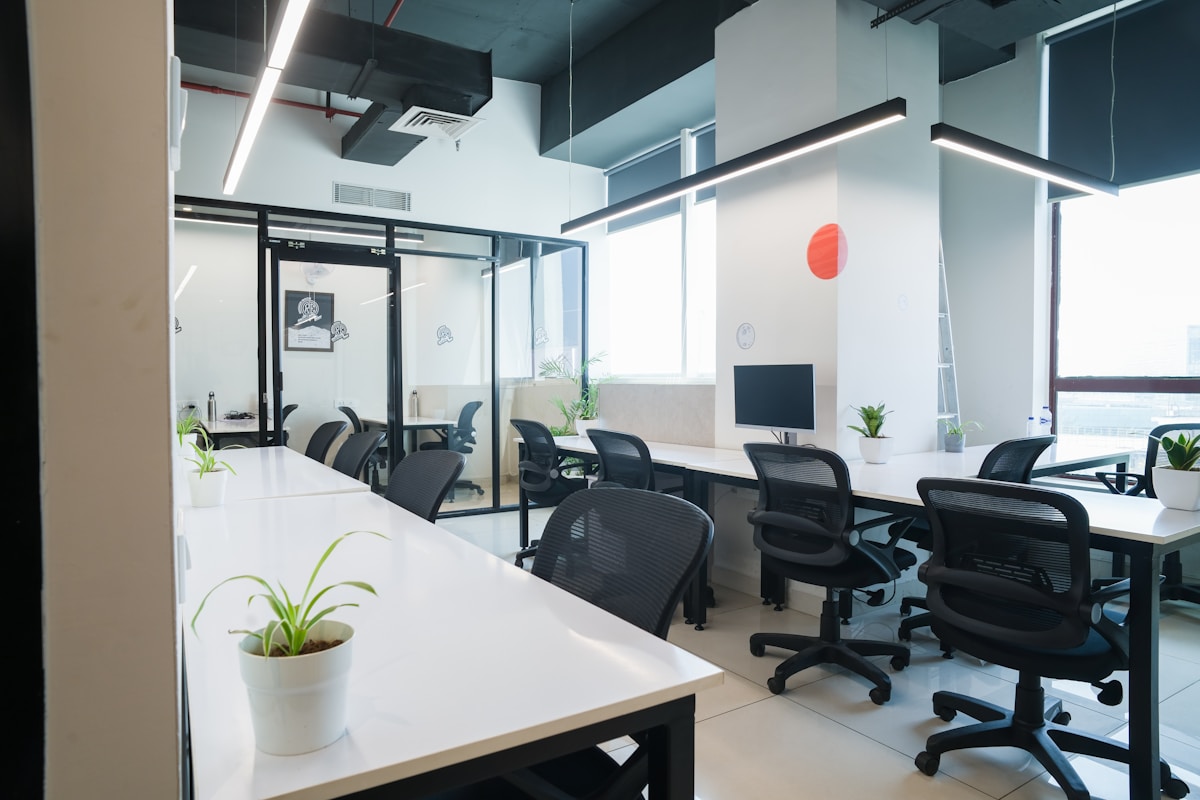 Espace de travail moderne avec bureaux, chaises et plantes d'intérieur.