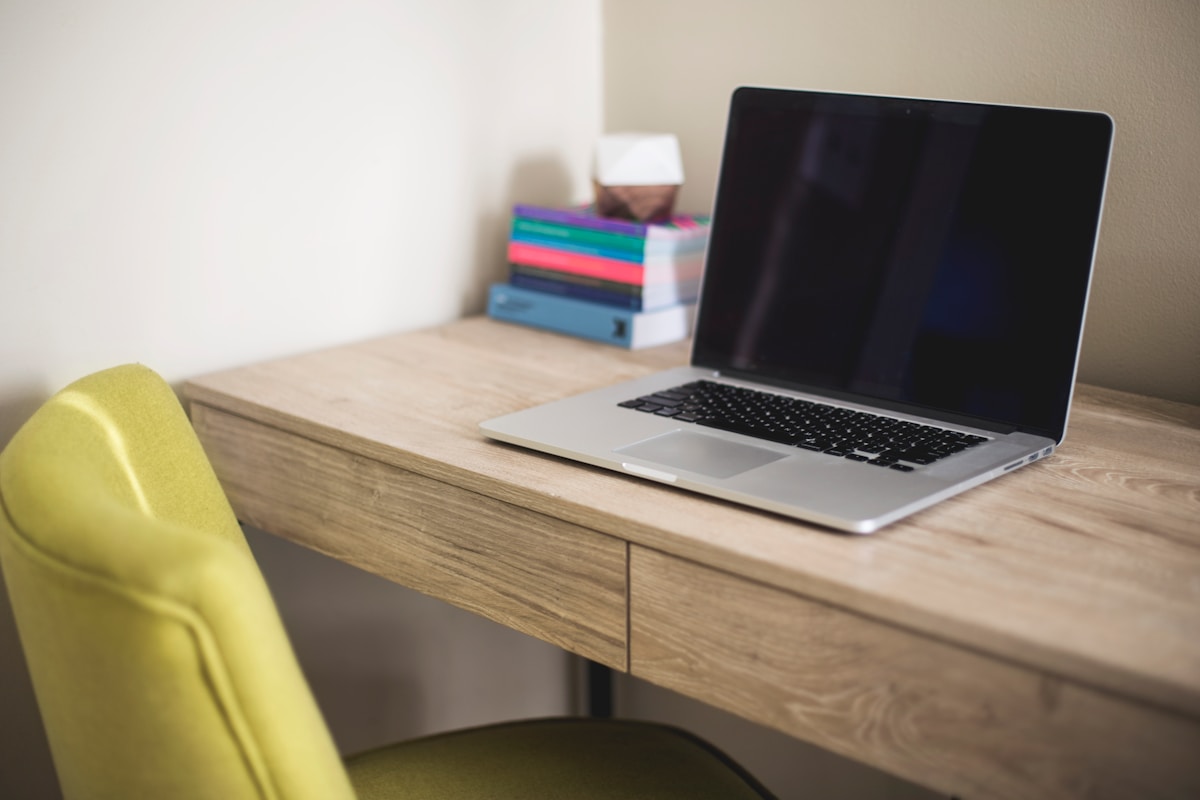 Bureau en bois avec ordinateur portable et livres.