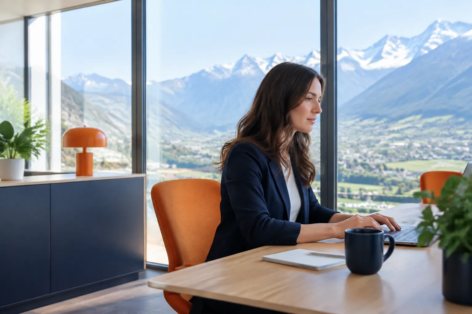 Femme travaillant sur ordinateur, montagnes enneigées en arrière-plan.